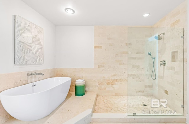 bathroom featuring independent shower and bath and tile walls