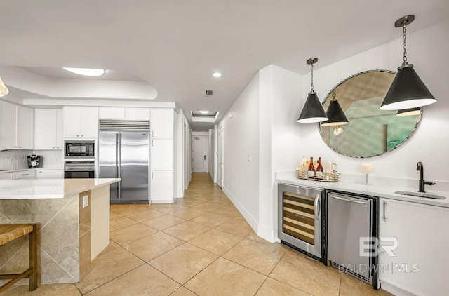 kitchen featuring white cabinets, built in appliances, wine cooler, sink, and light tile patterned floors