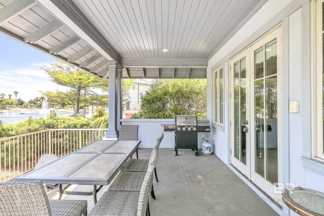 view of patio / terrace with a water view, area for grilling, french doors, and outdoor dining area