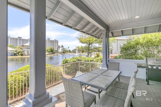 view of patio with grilling area, a water view, and outdoor dining area