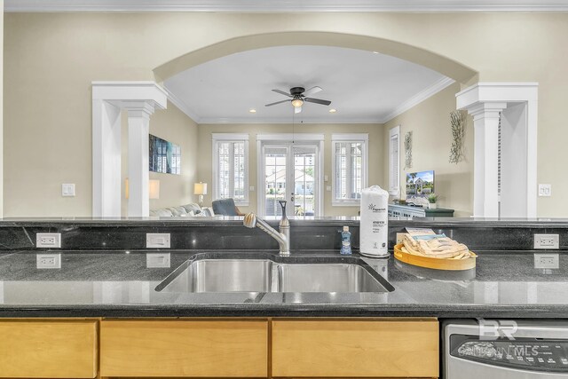 kitchen featuring dishwasher, a sink, open floor plan, arched walkways, and ornate columns