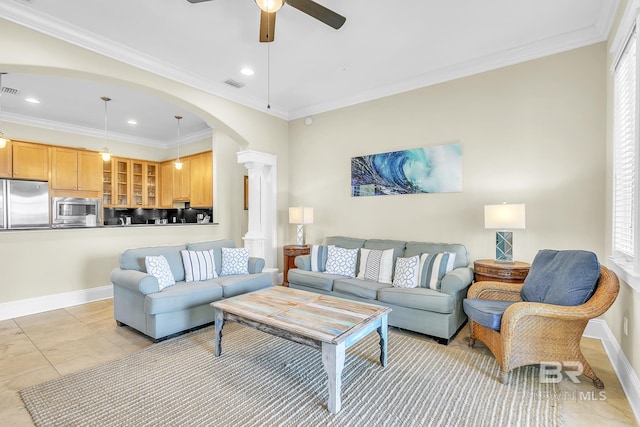 living area with a ceiling fan, decorative columns, baseboards, arched walkways, and ornamental molding