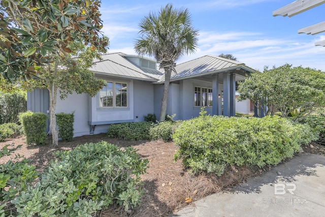 single story home featuring metal roof, stucco siding, and a standing seam roof