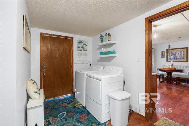 washroom with a textured ceiling, dark hardwood / wood-style floors, and washer and clothes dryer