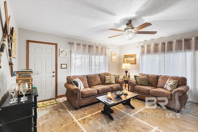 living room with an AC wall unit, ceiling fan, hardwood / wood-style floors, and a textured ceiling