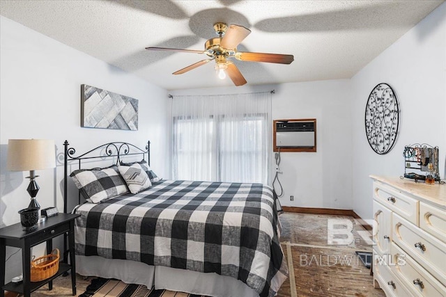 bedroom with a textured ceiling, an AC wall unit, and ceiling fan