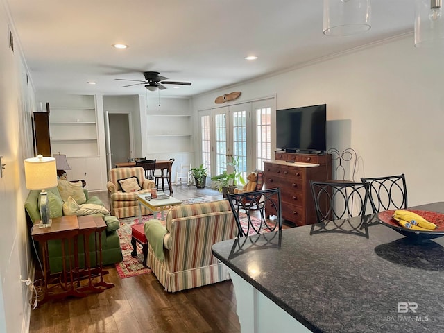 living room with built in features, crown molding, ceiling fan, and dark hardwood / wood-style floors