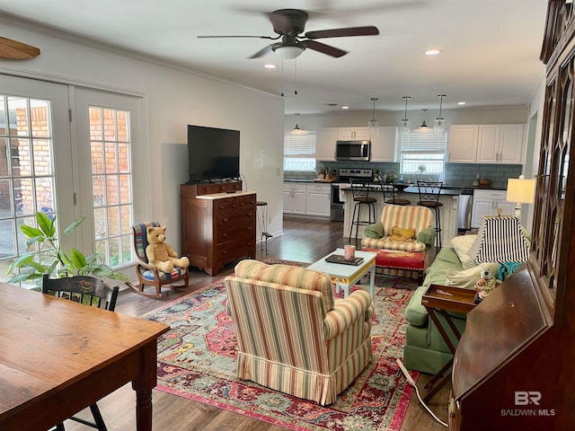 living room featuring ceiling fan, crown molding, wood-type flooring, and a healthy amount of sunlight