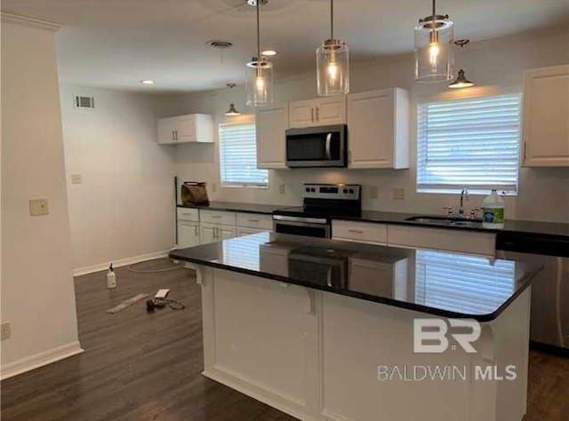 kitchen featuring dark hardwood / wood-style flooring, pendant lighting, appliances with stainless steel finishes, sink, and white cabinetry