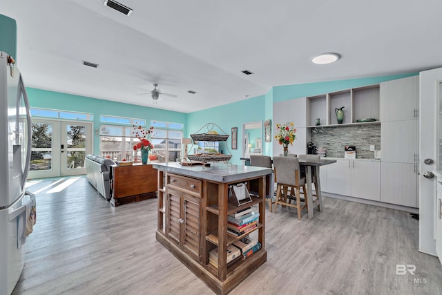 kitchen featuring light wood finished floors, visible vents, freestanding refrigerator, white cabinetry, and open shelves