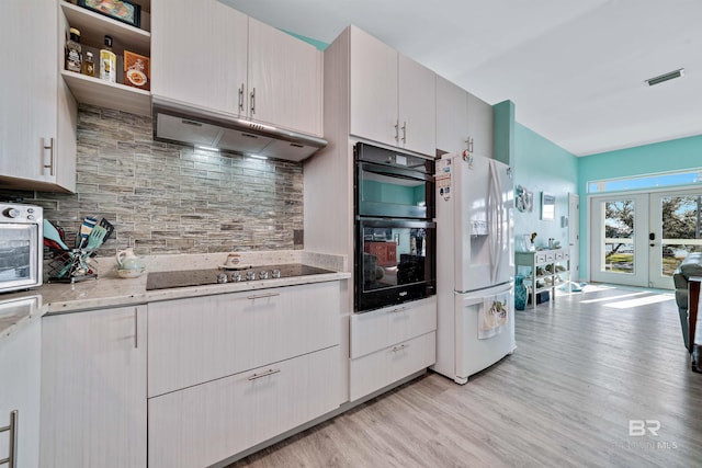 kitchen with tasteful backsplash, under cabinet range hood, french doors, light wood-type flooring, and black appliances