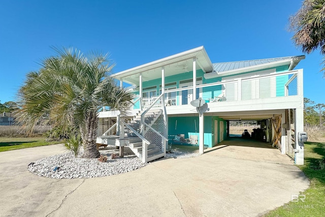 view of front of house with driveway, metal roof, a porch, and a carport