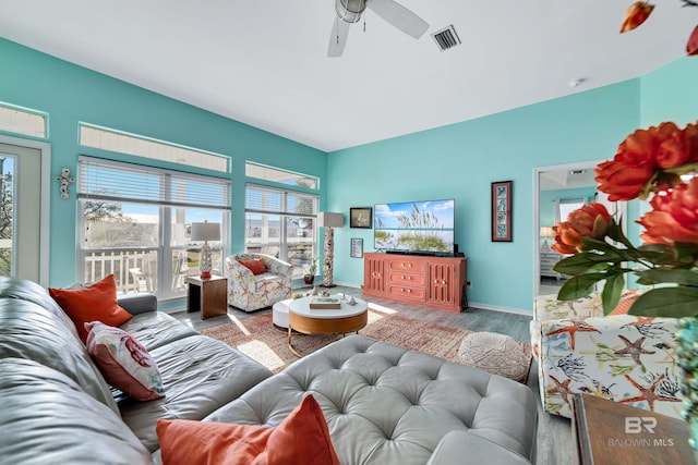 living area with baseboards, ceiling fan, visible vents, and wood finished floors