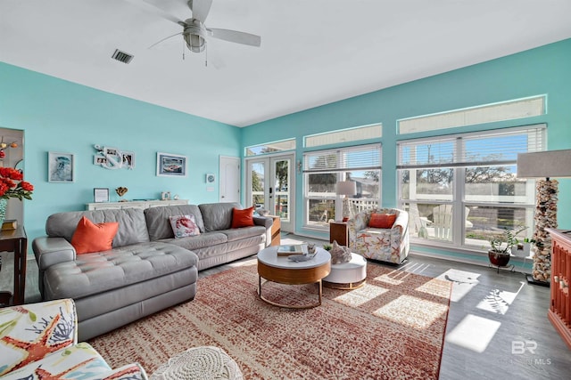 living area featuring french doors, visible vents, ceiling fan, and wood finished floors