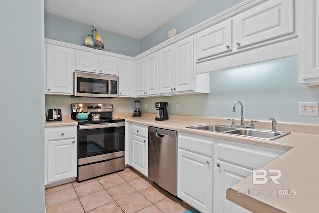 kitchen featuring sink, white cabinets, stainless steel appliances, and light tile patterned floors