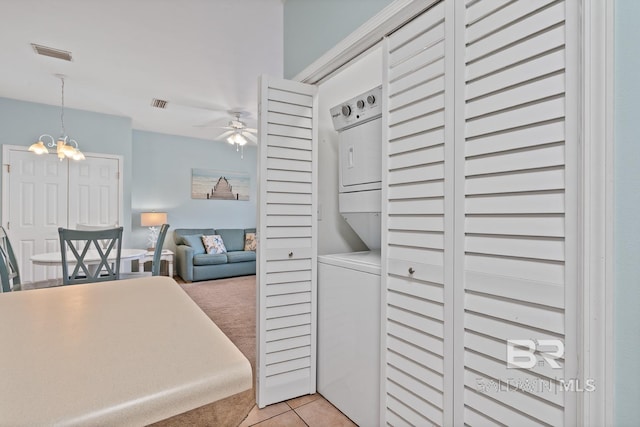 kitchen featuring decorative light fixtures, light tile patterned flooring, ceiling fan with notable chandelier, and stacked washer and clothes dryer