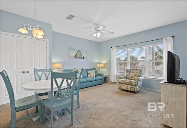 carpeted living room featuring ceiling fan with notable chandelier