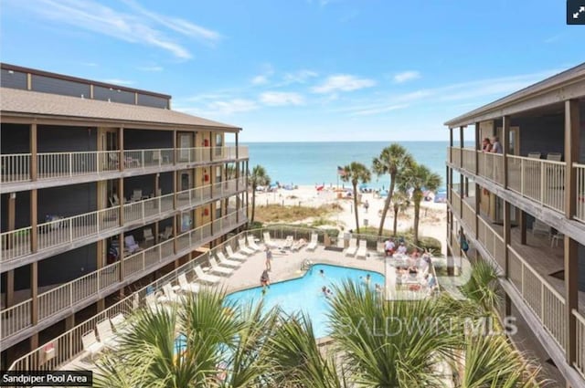 view of swimming pool featuring a beach view, a patio, and a water view