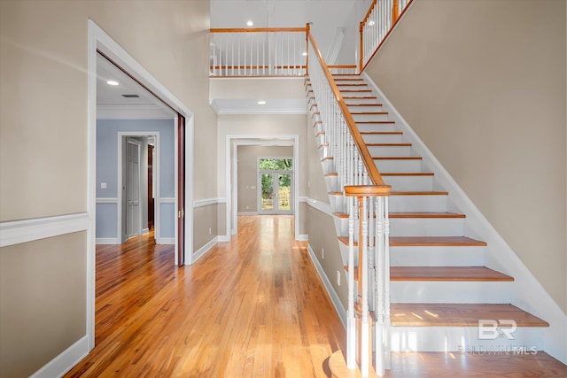 stairs with hardwood / wood-style floors and crown molding