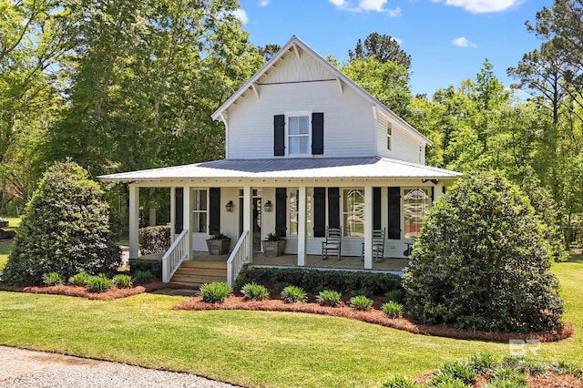 country-style home featuring a porch, metal roof, and a front lawn