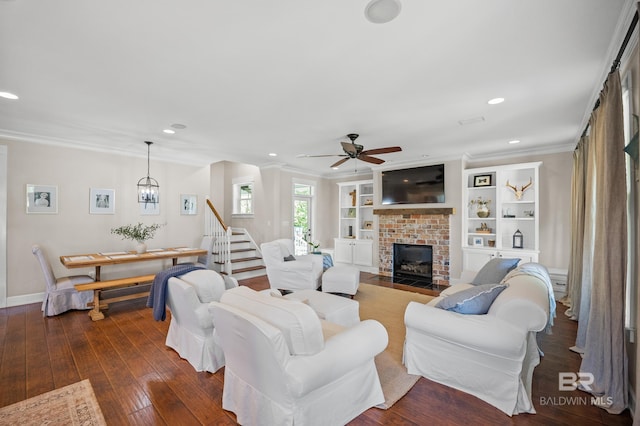 living room featuring baseboards, a fireplace, dark wood-style floors, crown molding, and a ceiling fan