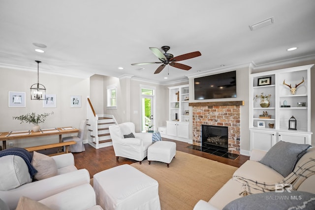 living room featuring ornamental molding, stairs, a brick fireplace, visible vents, and dark wood finished floors