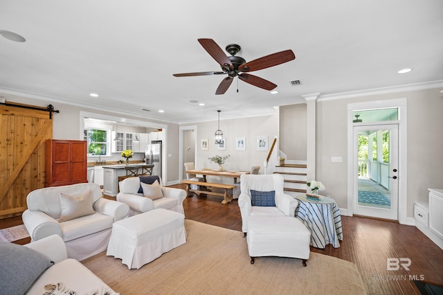 living room featuring ornamental molding, visible vents, a barn door, wood finished floors, and stairs