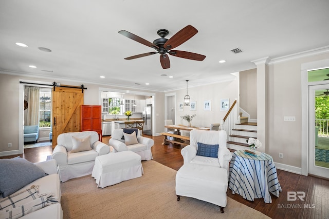 living room featuring visible vents, a barn door, ornamental molding, stairway, and wood finished floors