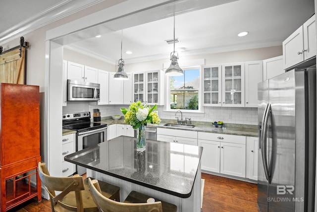 kitchen featuring visible vents, a sink, a kitchen breakfast bar, crown molding, and stainless steel appliances