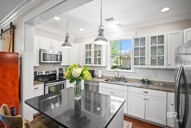 kitchen with visible vents, a center island, a sink, appliances with stainless steel finishes, and crown molding