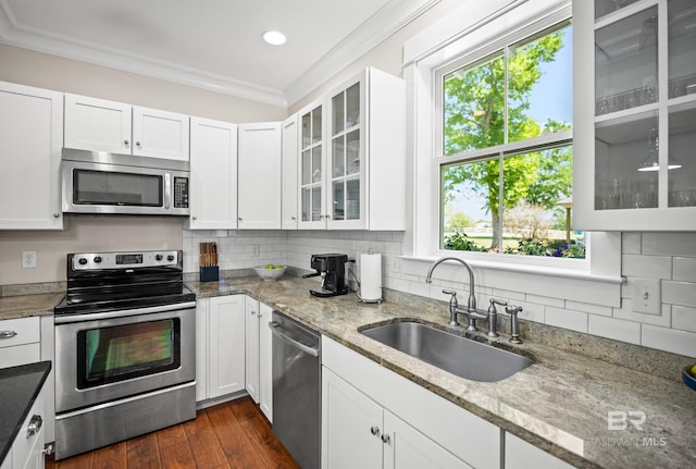 kitchen featuring decorative backsplash, a sink, ornamental molding, and appliances with stainless steel finishes