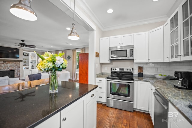 kitchen with glass insert cabinets, crown molding, white cabinets, dark wood-type flooring, and appliances with stainless steel finishes