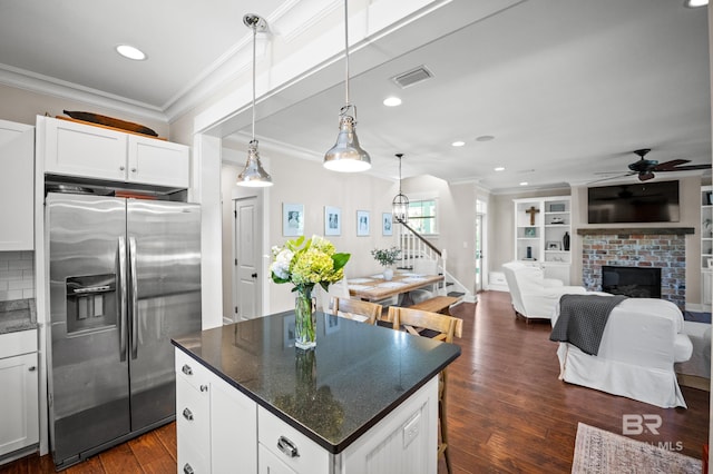 kitchen with crown molding, dark wood-type flooring, a ceiling fan, a center island, and stainless steel fridge
