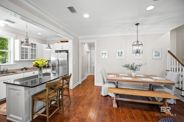 dining space featuring visible vents, baseboards, an inviting chandelier, dark wood finished floors, and crown molding
