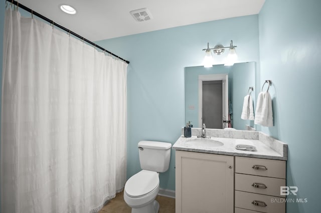 bathroom featuring toilet, vanity, baseboards, and visible vents