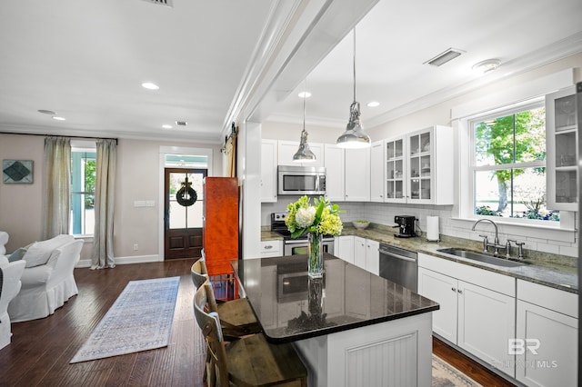 kitchen featuring glass insert cabinets, a sink, crown molding, stainless steel appliances, and decorative backsplash