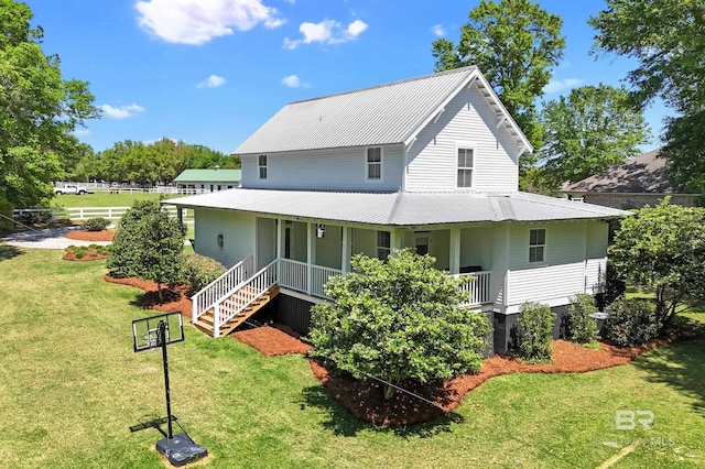 back of house with metal roof, a lawn, and covered porch