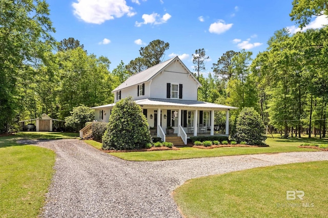 view of front of property featuring curved driveway, a front lawn, an outbuilding, metal roof, and covered porch