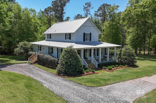 farmhouse-style home with covered porch, a front lawn, and metal roof