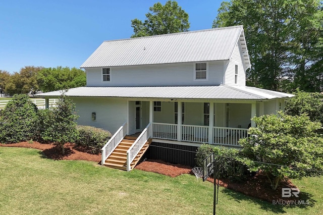 farmhouse inspired home with stairway, a front yard, metal roof, and covered porch
