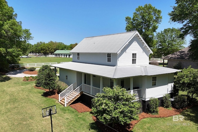 rear view of house with fence, covered porch, metal roof, and a lawn