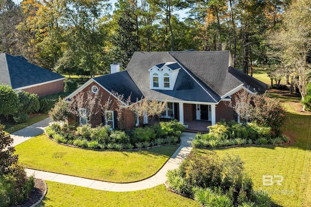 view of front of property with brick siding, a front lawn, covered porch, and a chimney