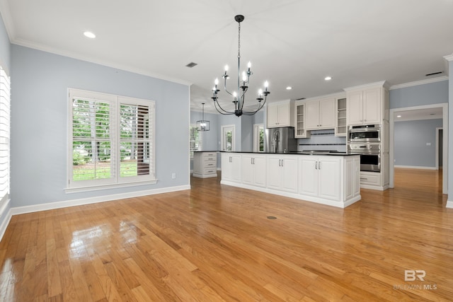 kitchen with dark countertops, baseboards, a notable chandelier, ornamental molding, and stainless steel appliances