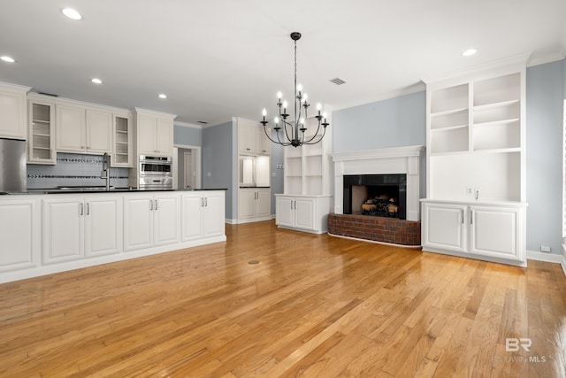 unfurnished living room featuring light wood-style floors, recessed lighting, and a notable chandelier