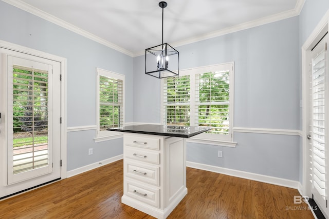 unfurnished dining area featuring baseboards, ornamental molding, wood finished floors, and a chandelier