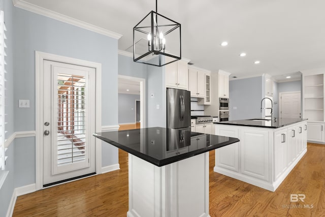 kitchen featuring crown molding, appliances with stainless steel finishes, an island with sink, and a sink