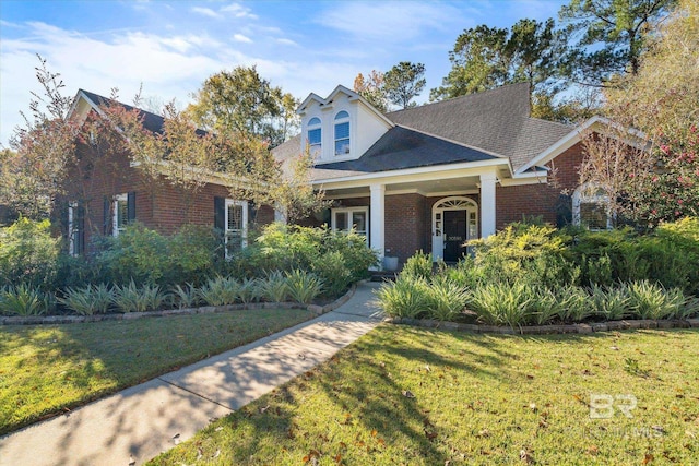 view of front of home with brick siding, a shingled roof, and a front lawn