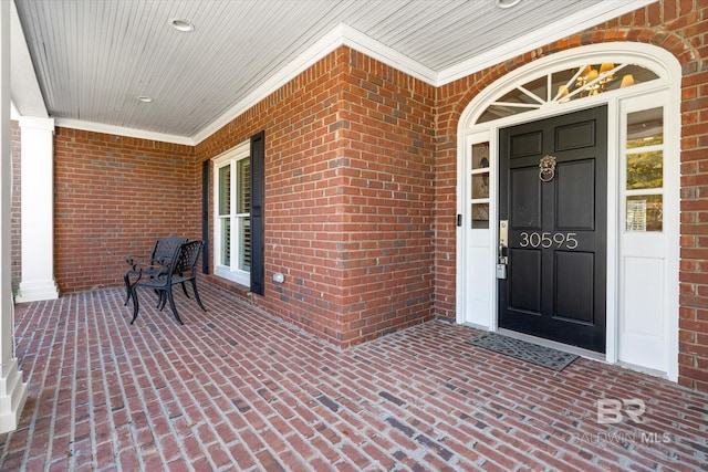 entrance to property featuring brick siding and a porch