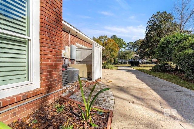 view of side of property featuring central air condition unit and brick siding