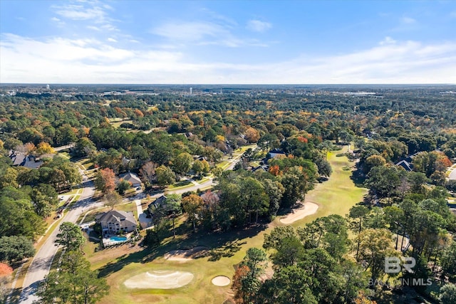 drone / aerial view with view of golf course and a wooded view
